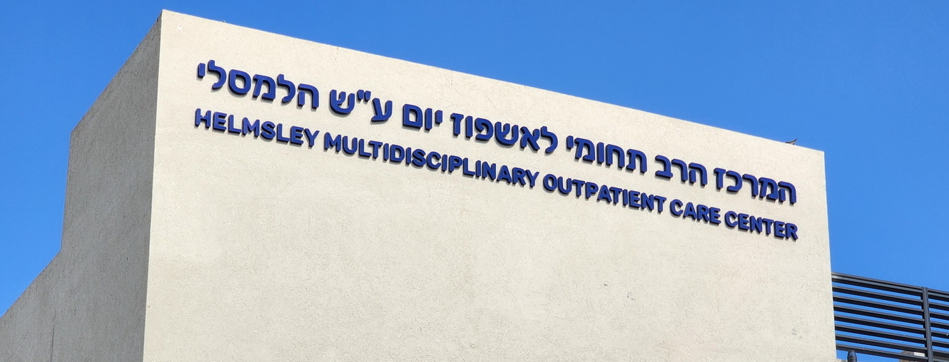 Photo of building with sign in Hebrew and English: "Helmsley Multidisciplinary Outpatient Care Center"